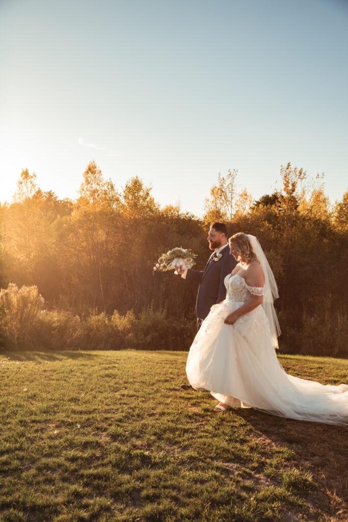 Bride and groom walking in a field during golden hour